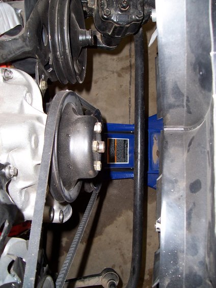 Engine pulleys and belts with a blue hydraulic jack supporting a component