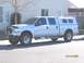 2004 Ford F-250 - This silver 2004 Ford F-250 Super Duty crew cab pickup truck is equipped with a camper shell and roof rack, seen from the side.