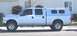 2004 Ford F-250 - Side view of a silver 2004 Ford F-250 pickup truck equipped with a camper shell and roof rack.