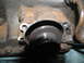 1978 Ford Bronco - A close-up view of a transmission component, showing its gray surface and black accents within a rusty housing.