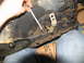 1978 Ford Bronco - A hand uses a wrench on a Ford transmission housing, likely during a repair or maintenance procedure.
