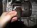 1978 Ford Bronco - Close-up of a hand holding a metal clip within a transmission assembly, likely during a tear-down or repair process.