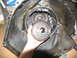 1978 Ford Bronco - A hand holds a transmission torque converter clutch in front of the transmission housing, likely during a tear-down or repair process.