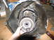 1978 Ford Bronco - A hand holds a torque converter in front of a disassembled transmission bell housing.