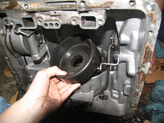Hand holding a large gear from inside a transmission housing