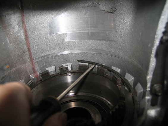 close-up of transmission internals with a screwdriver prying a metal ring