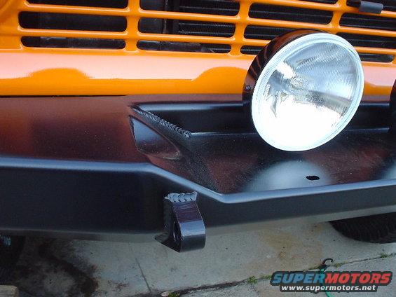 Front of an orange vehicle with a black off-road bumper and a round headlight