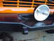 1977 Ford Bronco - Close-up of the front bumper and grille of an orange vehicle with an auxiliary light.