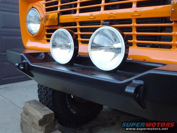 Orange 1977 Ford Bronco front end with black aftermarket bumper and two round fog lights