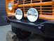 1977 Ford Bronco - Orange 1977 Ford Bronco front end with black aftermarket bumper and two round fog lights.