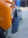 1977 Ford Bronco - Close-up view of the front bumper and headlight assembly on an orange 1977 Ford Bronco.