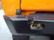1977 Ford Bronco - The rear bumper of an orange vehicle shows a black textured finish and a visible tow hitch receiver.