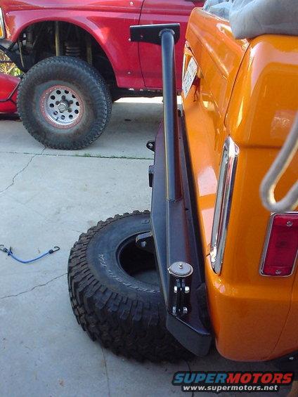 Orange SUV parked next to a red truck. Spare tire is mounted on the back of the orange SUV