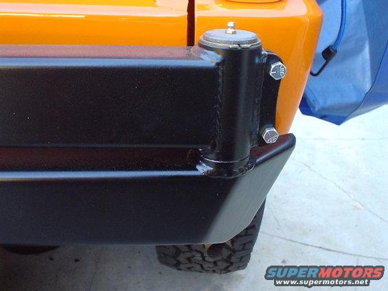 Orange 1977 Ford Bronco rear corner with black aftermarket bumper mount and tire visible