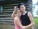 2001 BMW 3 Series - A couple poses for a photo in front of a rustic log cabin with trees in the background.