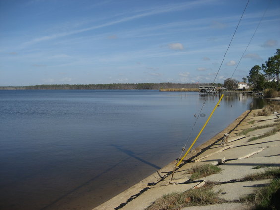 Fishing rods leaning on a concrete embankment next to a wide body of water