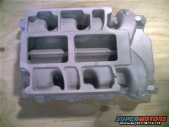 Aluminum intake manifold with multiple runners on a wooden surface