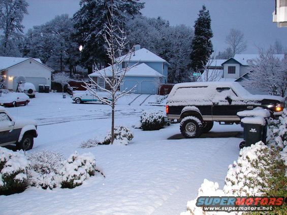 1996 Ford Bronco parked in driveway during snowfall, with other vehicles visible