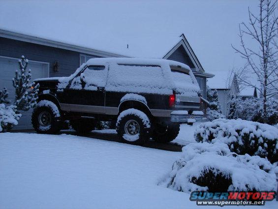 1996 Ford Bronco parked in driveway covered in snow, side view