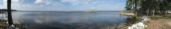 Panoramic lake scene with an island and trees on the shore