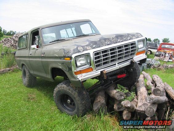 Green 1978 Ford Bronco with skull graphics on hood, lifted and on logs