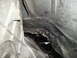 1997 Ford F-250 - The underside of a vehicle shows significant damage to a metal panel, revealing exposed layers beneath.