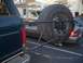 1988 Ford Bronco - The rear of a dark SUV is visible, equipped with an external spare tire carrier holding a large tire.
