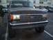 1988 Ford Bronco - A person adjusts the side mirror on a dark-colored Ford Bronco parked in a lot.