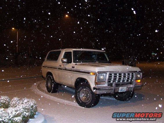 White 1978 Ford Bronco with chrome grille and side trim parked in snow