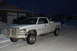 1996 Dodge 2500 - A white 1996 Dodge 2500 pickup truck is parked on a snow-covered street in front of a garage at night.