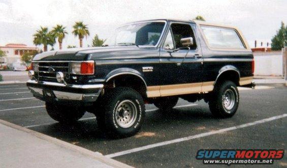 1991 Ford Bronco parked in a lot, dark blue with tan trim