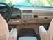 1992 Ford Bronco - The dashboard and interior of a 1992 Ford Bronco are visible, with a light blue vehicle in the background.