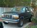 1992 Ford Bronco - A black 1992 Ford Bronco is parked in front of a white picket fence and trees.