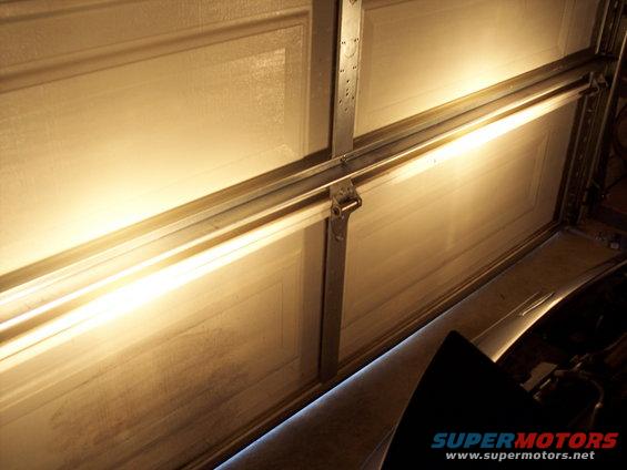 Interior of a garage door with bright lights illuminating the tracks and panels