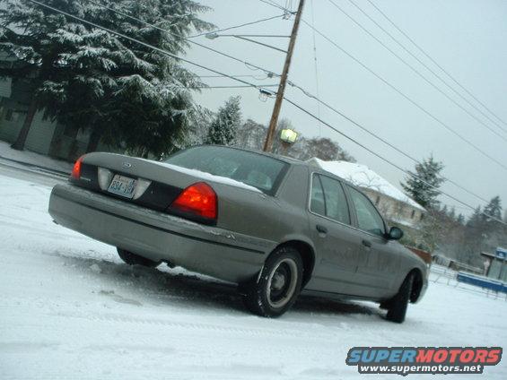 Gray 2000 Ford Crown Victoria in snow, rear 3/4 view
