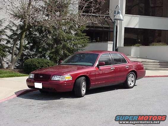 Red 2002 Ford Crown Victoria sedan parked on asphalt with a building in the background