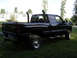 2002 Dodge 2500 - This black pickup truck features prominent dual exhaust stacks, visible from a 3/4 front perspective.