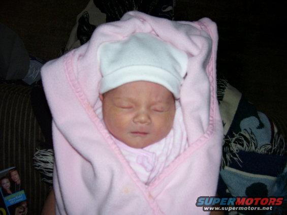 Baby wrapped in pink blanket and white hat, sleeping