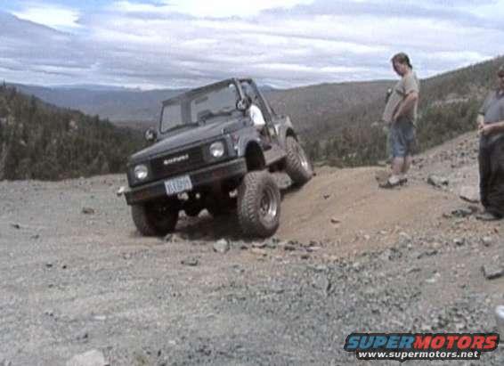 Black off-road SUV with lifted suspension on a dirt hill