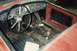 1959 MG A - The interior of a red 1959 MG A shows a worn dashboard, steering wheel, and floor panels.