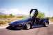 1973 Ford Ranchero - This dark blue sports car features distinctive gullwing doors, photographed in a desert environment.