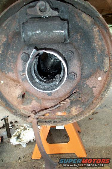 Close-up of a rusty brake drum assembly with a damaged wheel cylinder