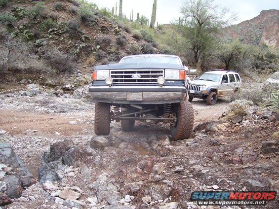 1991 Ford Bronco front view on rocky trail with Jeep in background