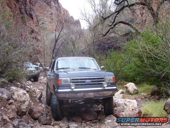 1991 Ford Bronco navigating a rocky canyon trail with another SUV behind it