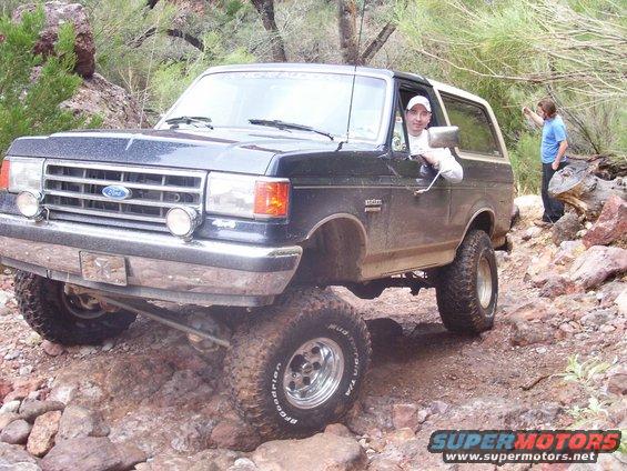 1991 Ford Bronco navigating a rocky trail with a driver and passenger visible