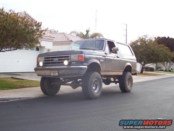 Dark gray lifted Ford Bronco with large tires parked on a residential street