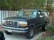 1992 Ford Bronco - A dark blue 1992 Ford Bronco is parked in a driveway with a white picket fence in the background.