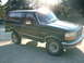 1992 Ford Bronco - A 1992 Ford Bronco is shown from the front three-quarter view, parked on a concrete surface with trees in the background.