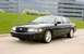 2003 Mercury Marauder - A black 2003 Mercury Marauder is shown driving on a road with a grassy hill and a modern building behind it.