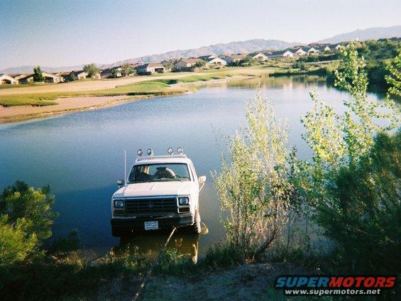 White SUV with roof lights partially in water, front view